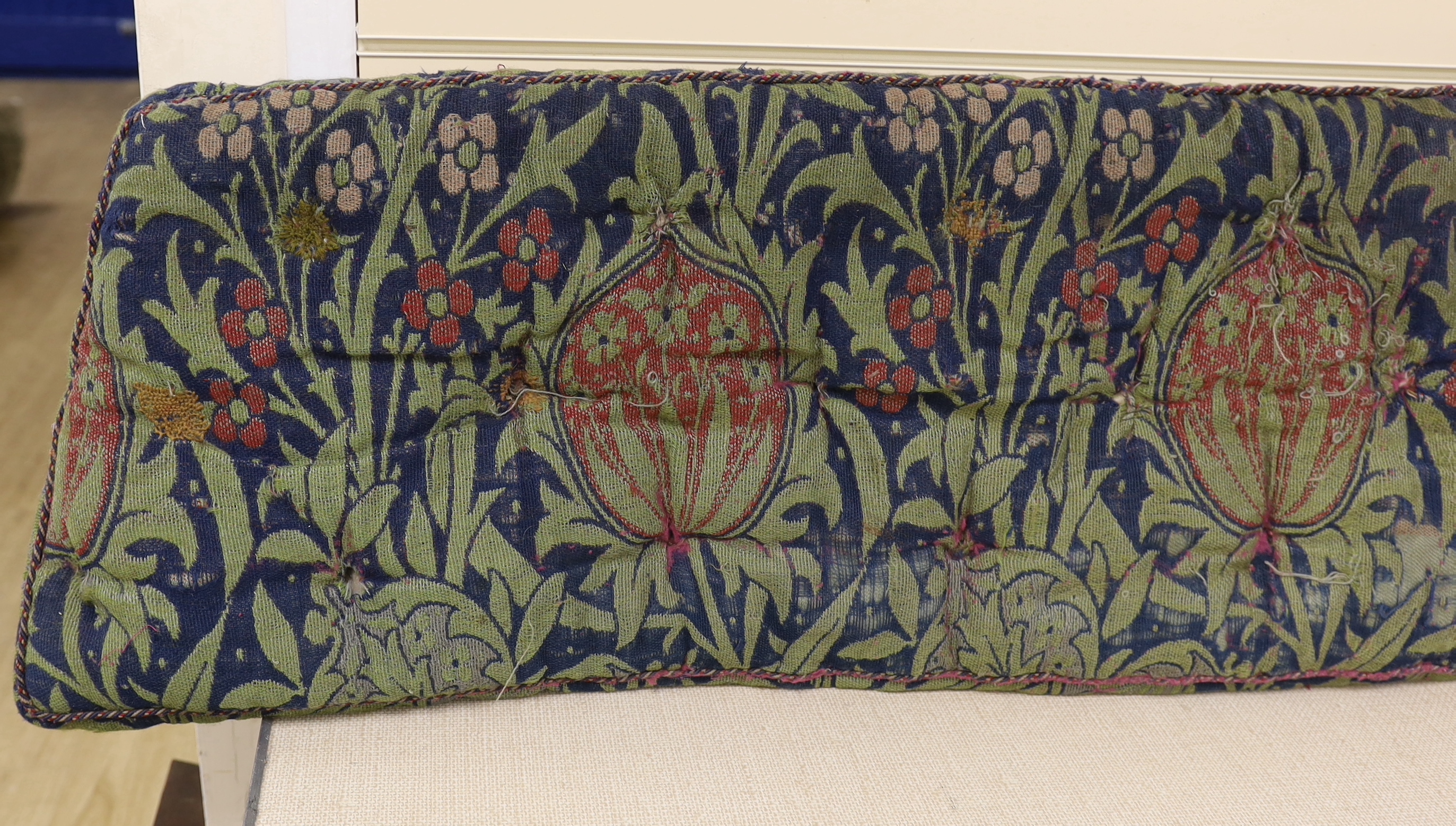 A William Morris Elmore, wool and mohair woven panel by J H Dearle circa 1900, used to cover a buttoned and braided window seat cushion, 196cm wide (at widest point) x 38cm deep, Please note this lot attracts an addition
